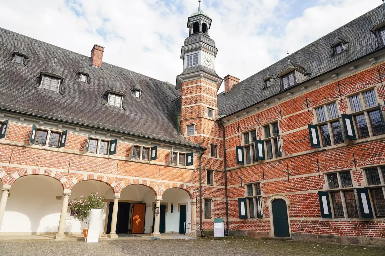 Innenhof von Schloss Reinbek mit Backsteinfassade, Arkaden und Turm