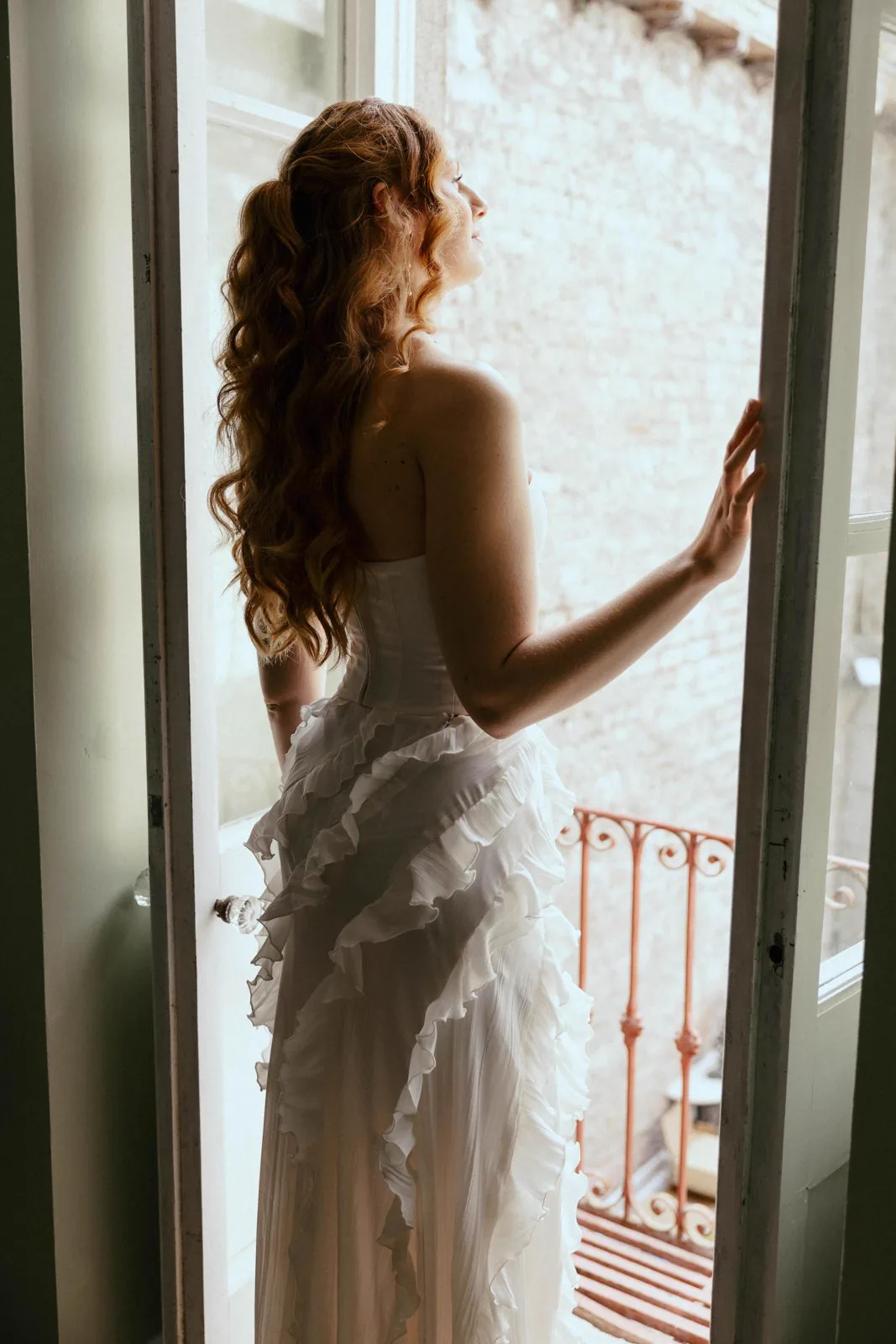 Braut im weißen Kleid am Fenster